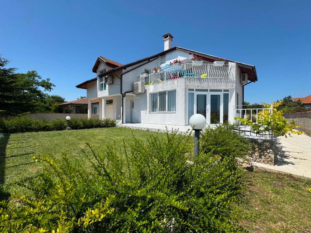 a white house with a balcony on top of it at Guest house FantasY in Tyulenovo