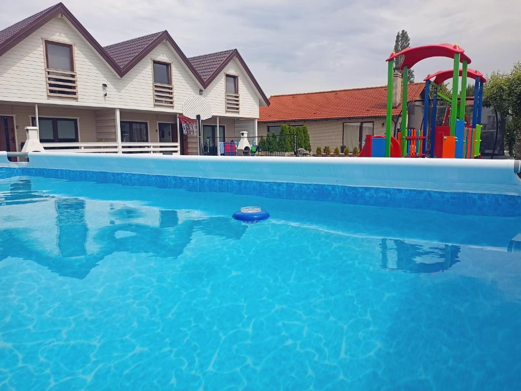 a swimming pool with a playground in front of a house at Domki Platinium Sianożęty Ustronie Morskie in Sianozety