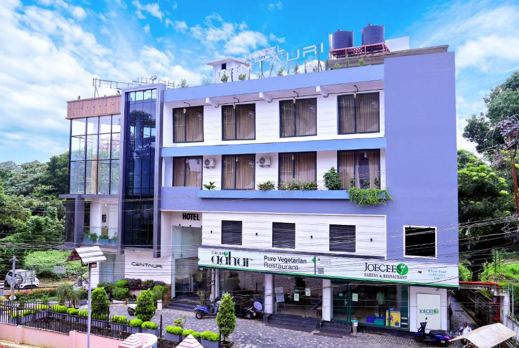 a white building with a sign on it at Hotel Centauri in Thiruvalla