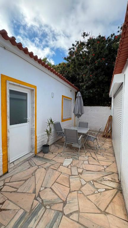 a patio with chairs and a table and an umbrella at Casinha da Portela in Sintra