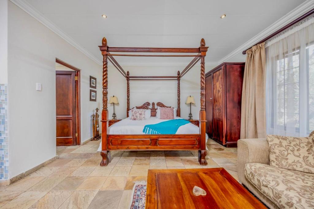 a bedroom with a canopy bed and a couch at 42onKing in Centurion