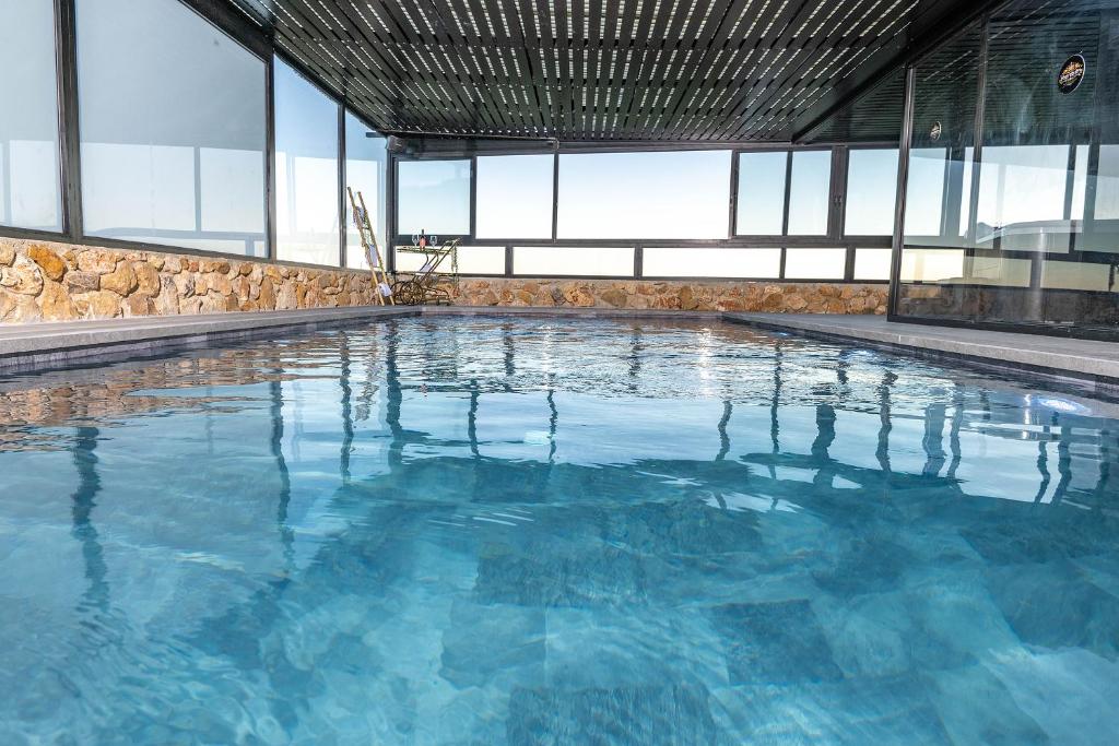 a large swimming pool with blue water in a building at כתר הגליל - ווילה יוקרתית עם 4 סוויטות ובריכה מפנקת in ‘Ein el Asad