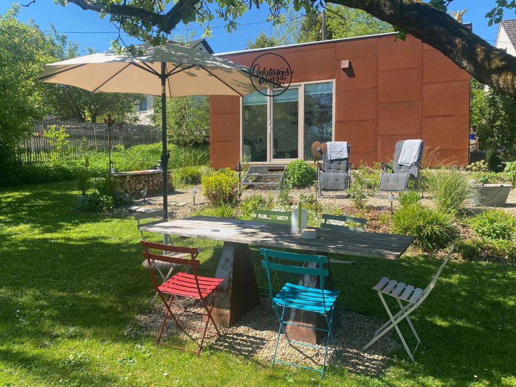 a table with chairs and an umbrella in a yard at Tiny House 47 in Egloffstein