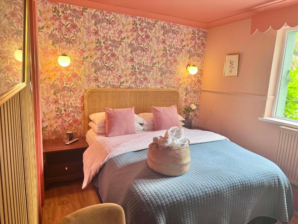 ein Schlafzimmer mit einem Bett mit rosa geblümter Tapete in der Unterkunft The Emsworth Hotel in Emsworth