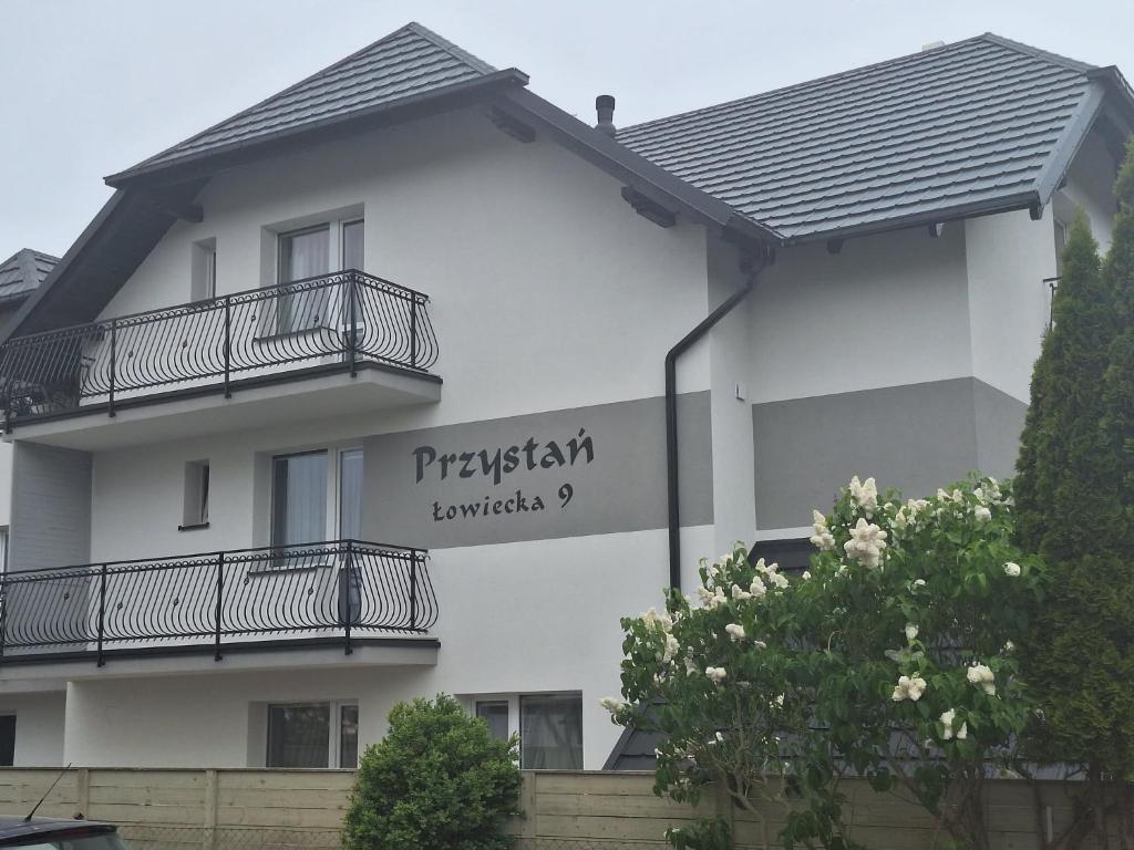 a white building with a sign on the side of it at Przystań Jagoda - pokoje i domki in Ostrowo