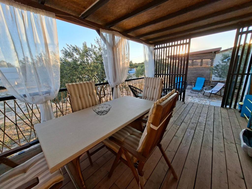 a porch with a table and chairs on a deck at Mobile home Magdalena in Pirovac