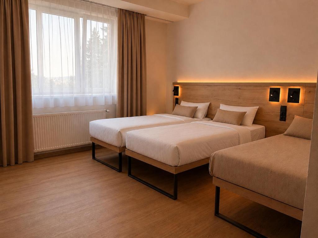 a hotel room with two beds and a window at Pension Klatovy in Klatovy