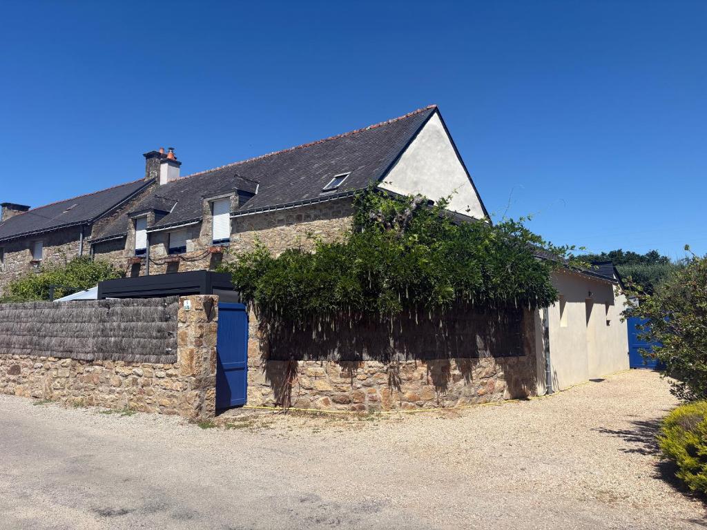 an old stone building with a blue door and vines at Les Terrasses de Rostevel in Brech