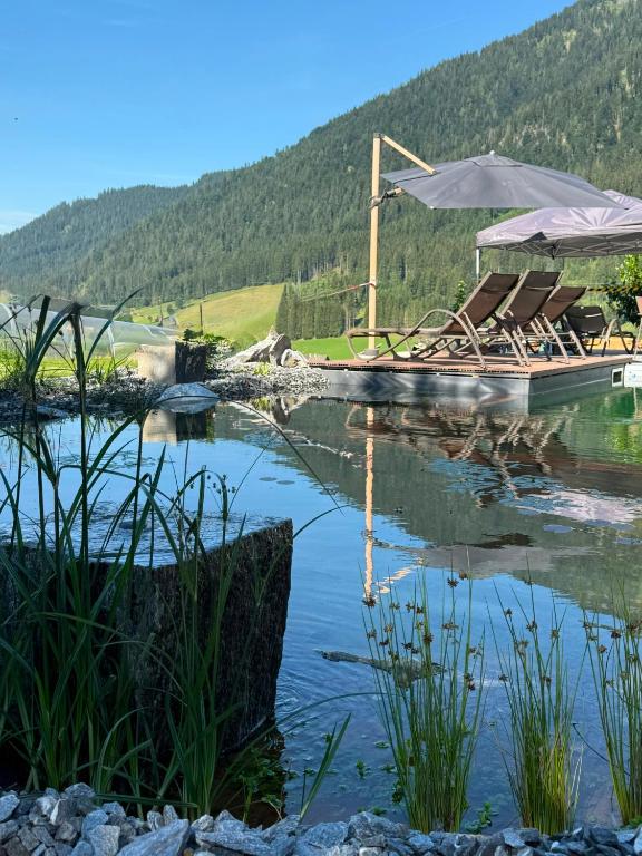 a pool of water with chairs and an umbrella at Landhotel Anna in Sankt Martin am Tennengebirge