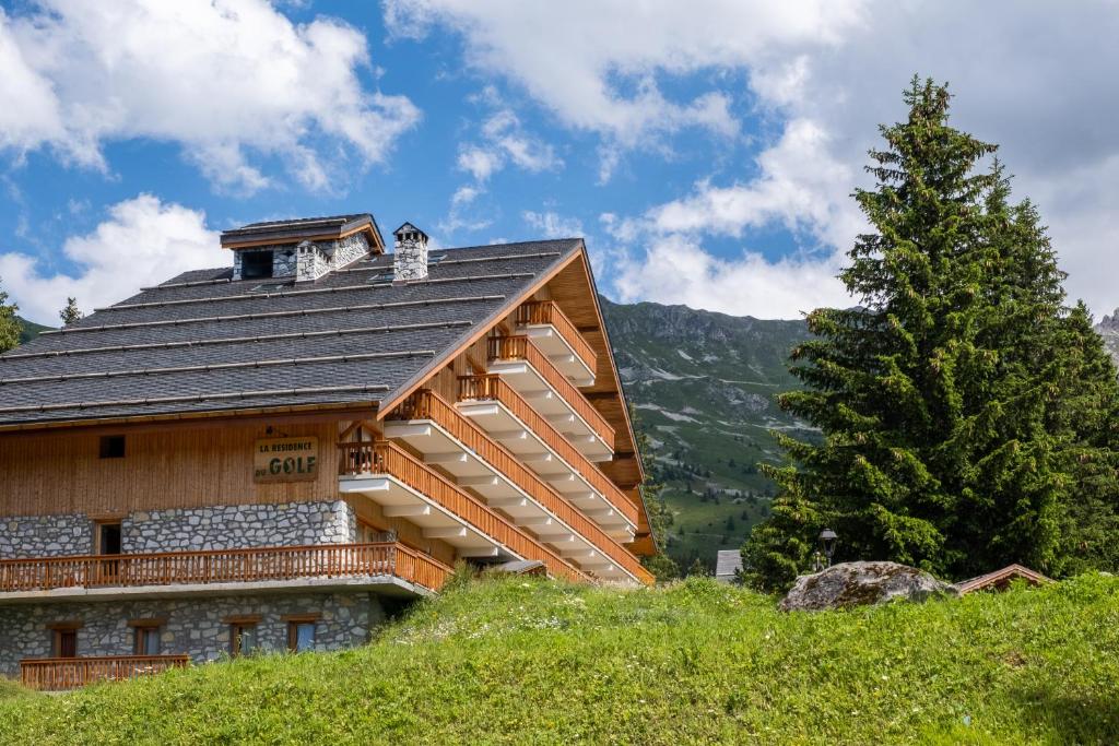 a log cabin on a hill with a tree at Résidence Le Golf in Méribel