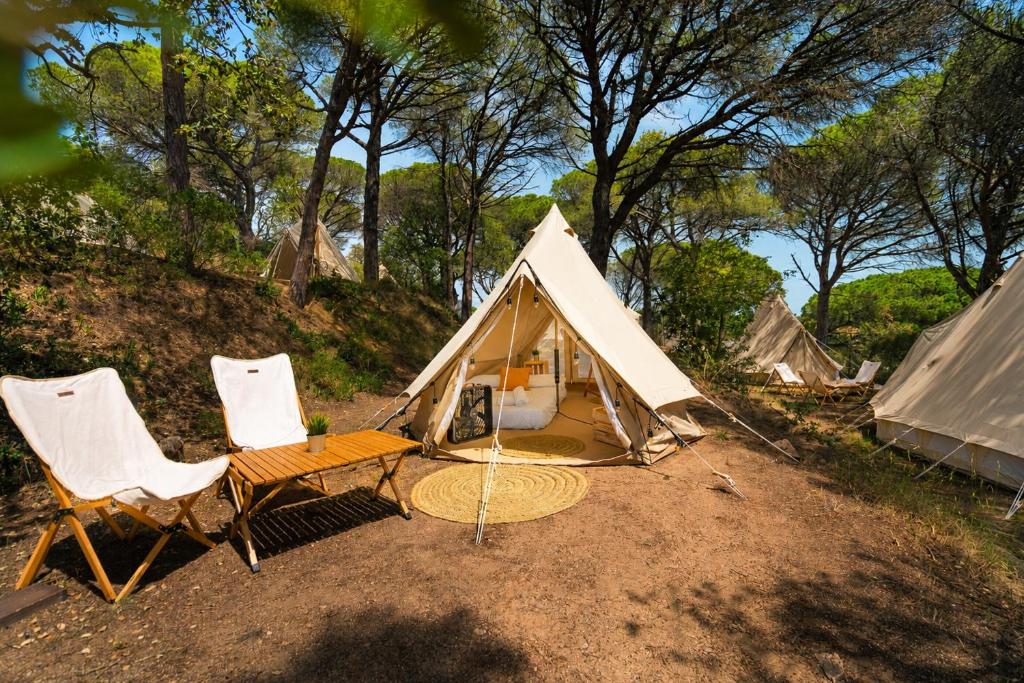 a tent with two chairs and a table and a bench at Kampaoh Calella de Palafrugell in Calella de Palafrugell
