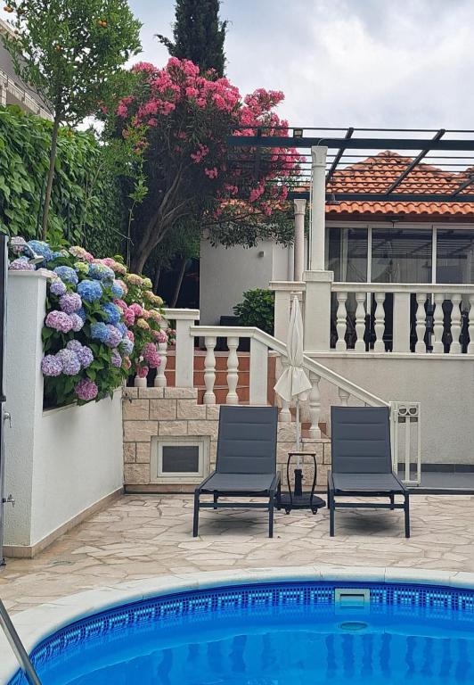 two chairs and a swimming pool in front of a house at Apartments Orange Tree in Cavtat