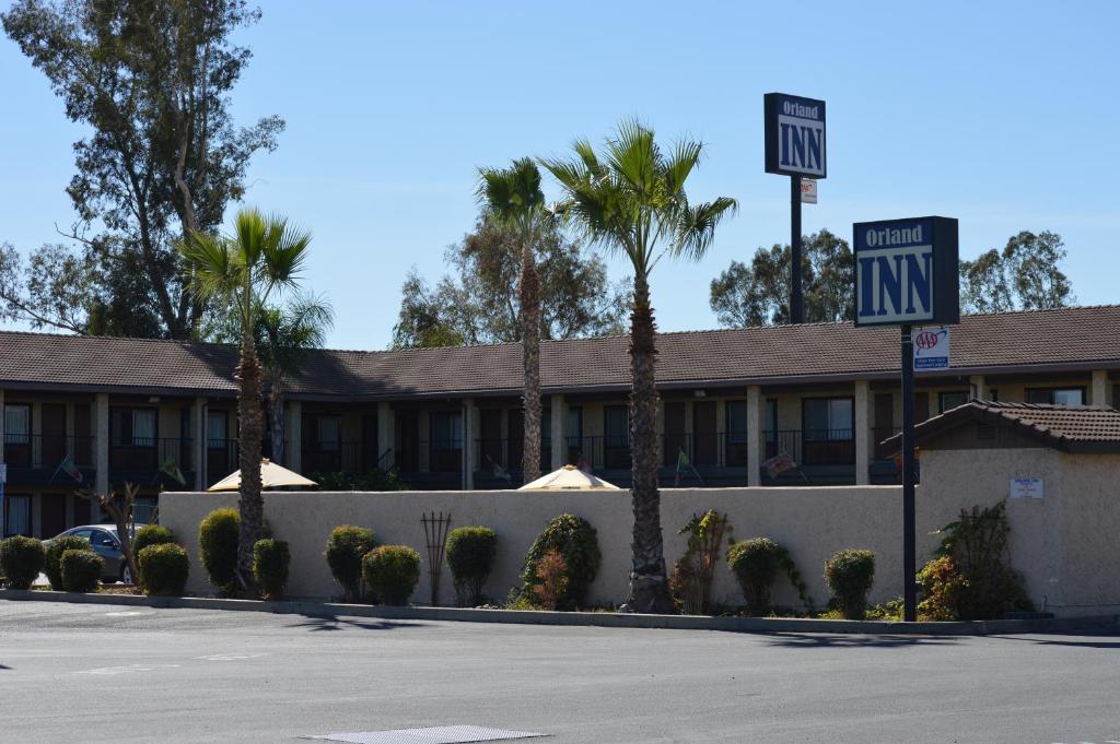 a hotel with palm trees and a one way sign at Orland Inn in Orland