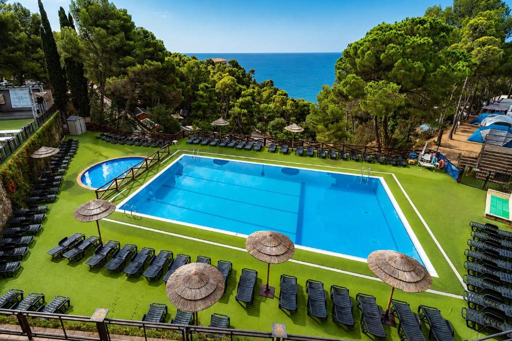 an image of a swimming pool with chairs and umbrellas at Kampaoh Tossa de Mar in Tossa de Mar