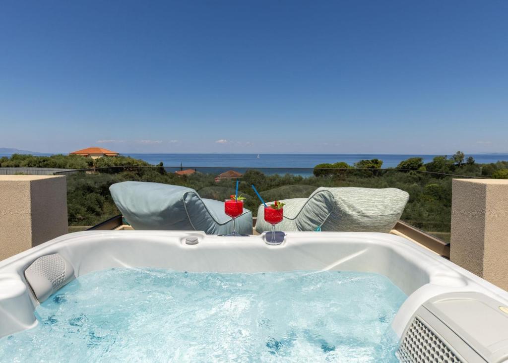 a jacuzzi tub with two drinks in it at Ark Luxury Suite, Hot tub & Sea Views, by ZanteWize in Tragaki