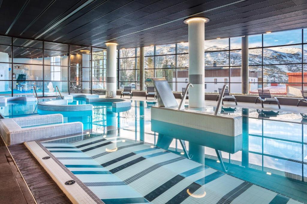 a swimming pool with blue tables and windows at Meliá Sierra Nevada in Sierra Nevada