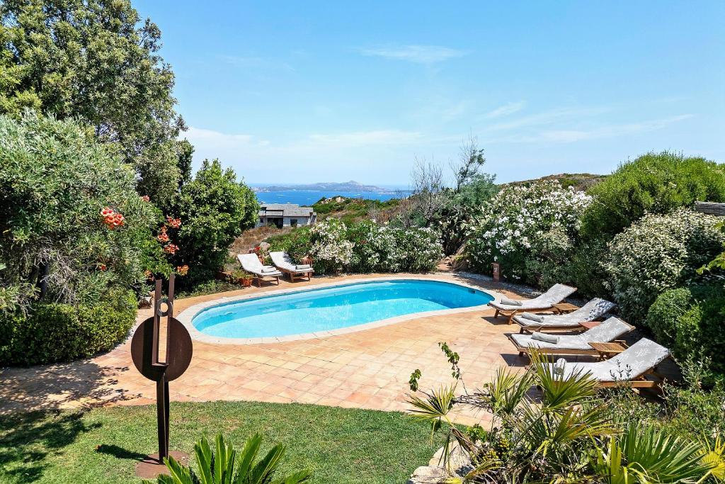 a swimming pool in a yard with chaise lounge chairs at Villa Sardinia Costa Smeralda in Arzachena
