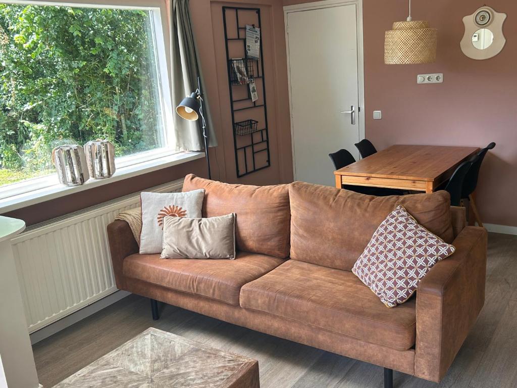 a living room with a brown couch and a table at Bungalow Halfweg in Ballum