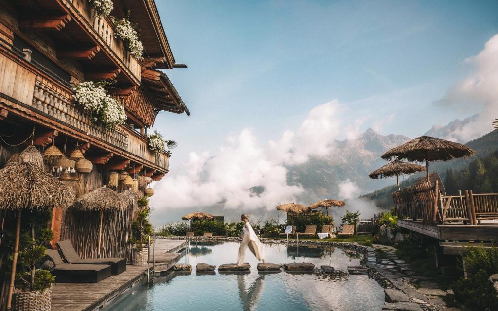 a woman jumping into a pool in a resort at Jufenalm BOHO & Wellnesshotel in Maria Alm am Steinernen Meer