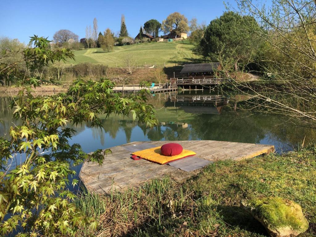 a small dock on a lake with a house at Les Temps Des Sources in Veyrines-de-Domme