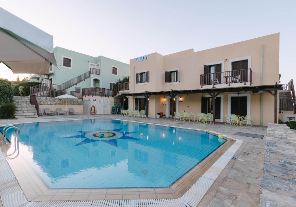 a large swimming pool in front of a building at Perla Apartments in Agia Pelagia