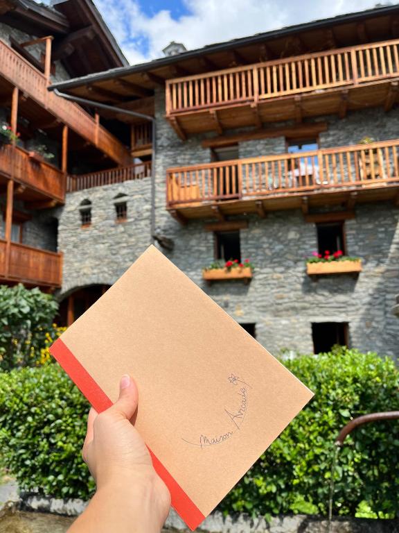 a person holding up a piece of paper in front of a building at Maison Arcade in La Salle