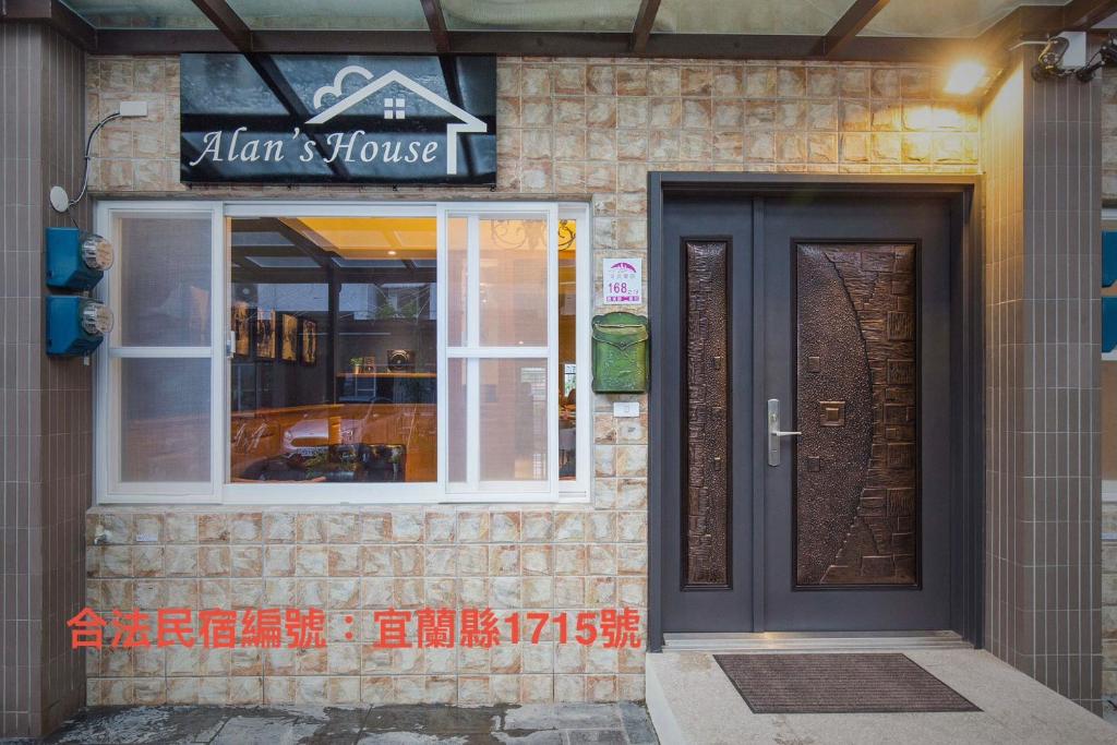 a building with a black door and a sign on it at Alan's House B&B in Jiaoxi