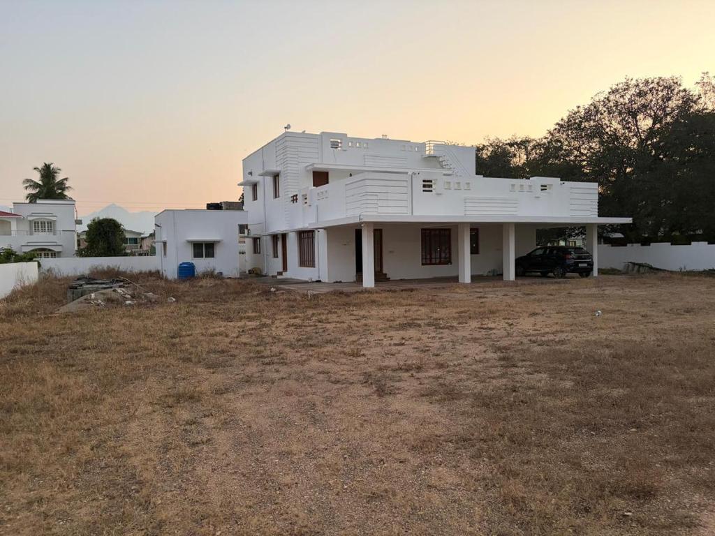 a white house sitting on top of a field at Senthur Bavanam in Udumalaippettai