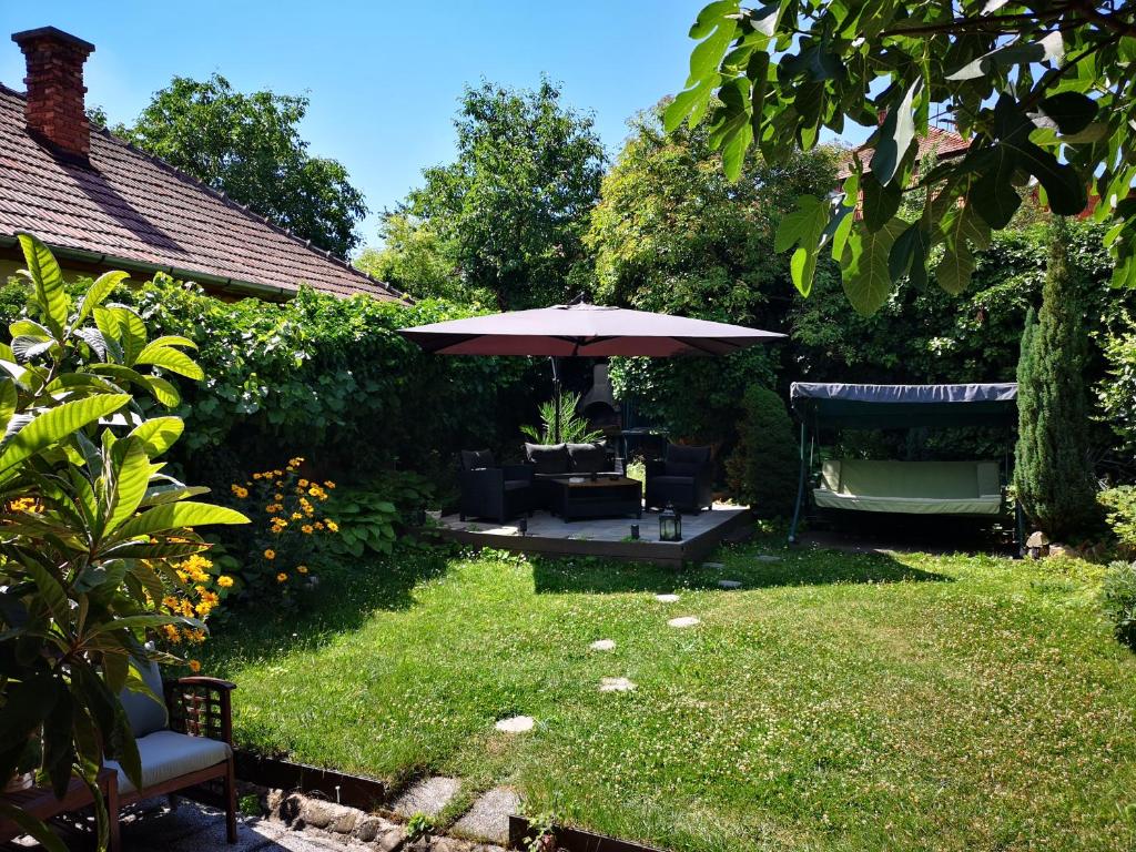 a garden with an umbrella and chairs and a bench at Villa-Hotel Escala in Cluj-Napoca
