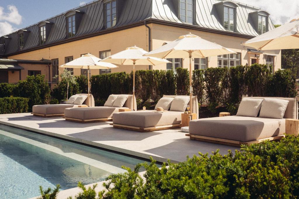 a row of lounge chairs and umbrellas next to a swimming pool at Varbergs Kusthotell in Varberg