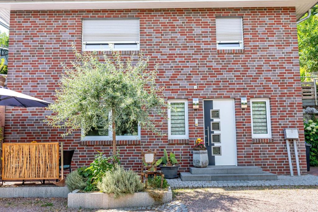 a red brick house with a tree in front of it at Weinbergschnecke Ferienwohnung in Efringen-Kirchen