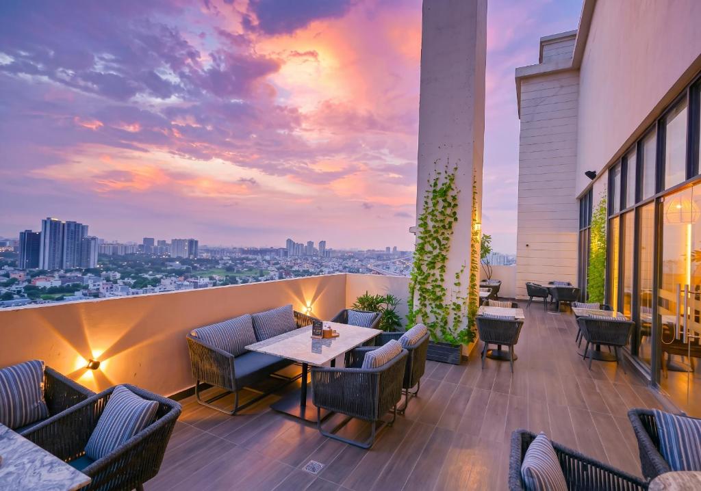 a rooftop patio with tables and chairs and a sunset at Rhythm Gurugram, Hotel & Suites, Sohna Road, Sector 68 in Gurgaon