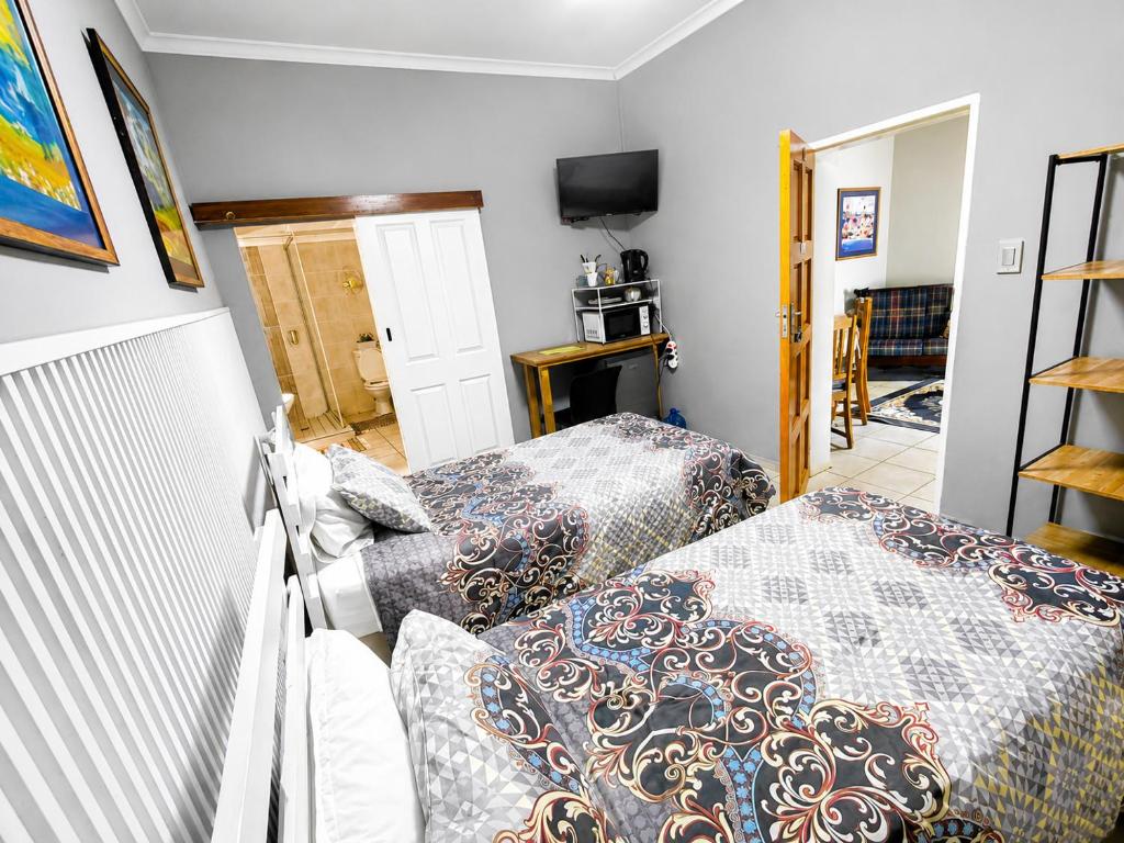 a bedroom with two beds and a tv at WHY NOT GUESTHOUSE in Bothaville