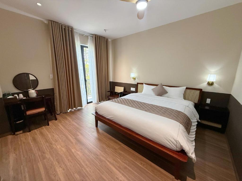 a bedroom with a large bed and a large window at Gemstay Hotel Hue in Thôn Trường Giang