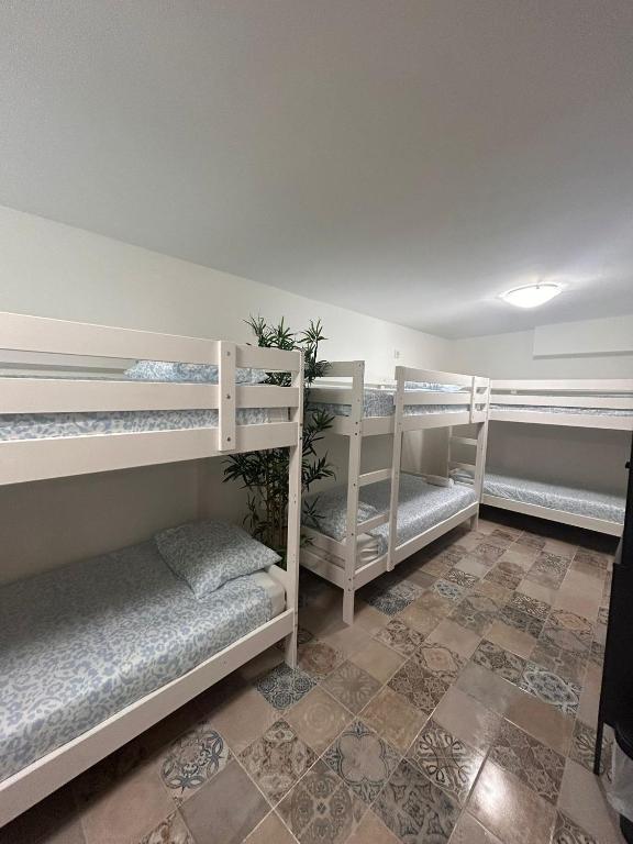 a room with three bunk beds and a tile floor at SIMPL hostel Oquendo in Madrid