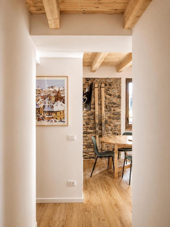 a dining room with a table and a stone wall at Clelia appartamento 6 posti vicino le piste da sci in Temù