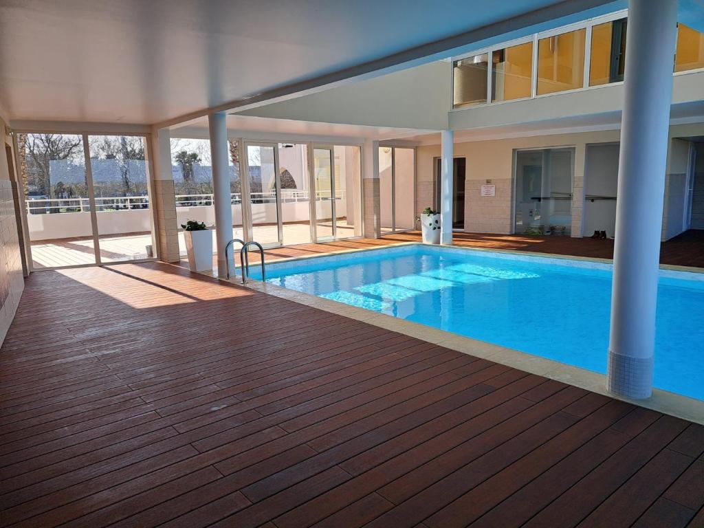 a swimming pool in a building with a wooden deck at Village Naturiste NATUREVA & SPA - Babylone NATURISME in Cap d'Agde