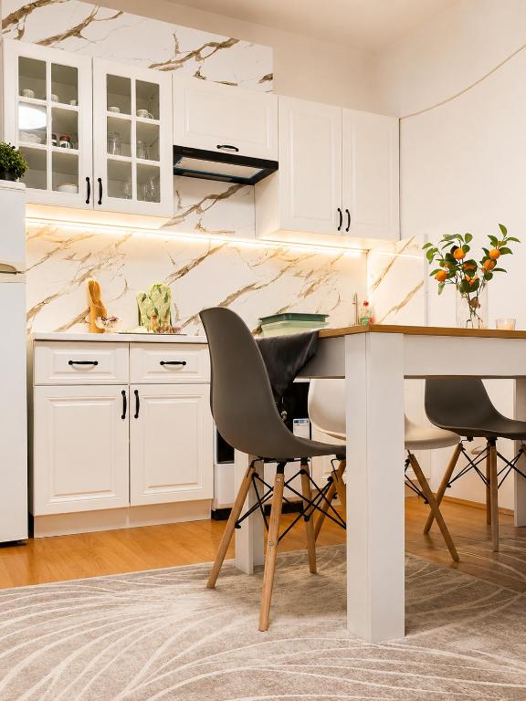 a kitchen with white cabinets and a table and chairs at G - Apartments in Kumanovo