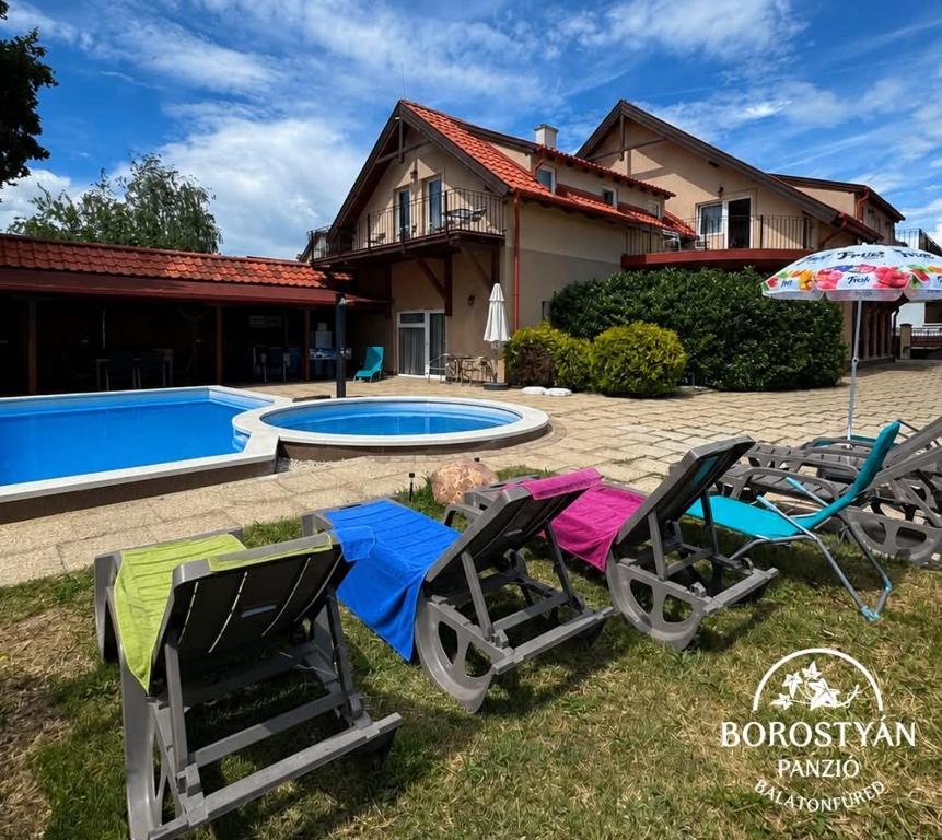 a house with a swimming pool and two lawn chairs and an umbrella at Balatonfüredi Borostyán Panzió in Balatonfüred