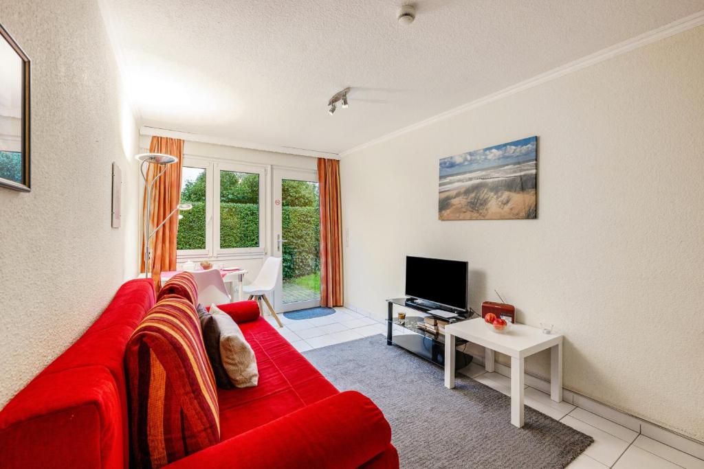 a living room with a red couch and a tv at Bungalow Westerland Kampstrasse in Westerland