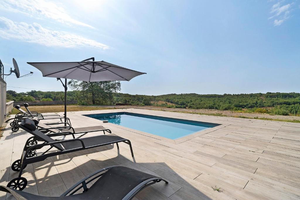 a patio with two chairs and an umbrella and a pool at Villa Alfaro in Saint-Cernin-de-Larche