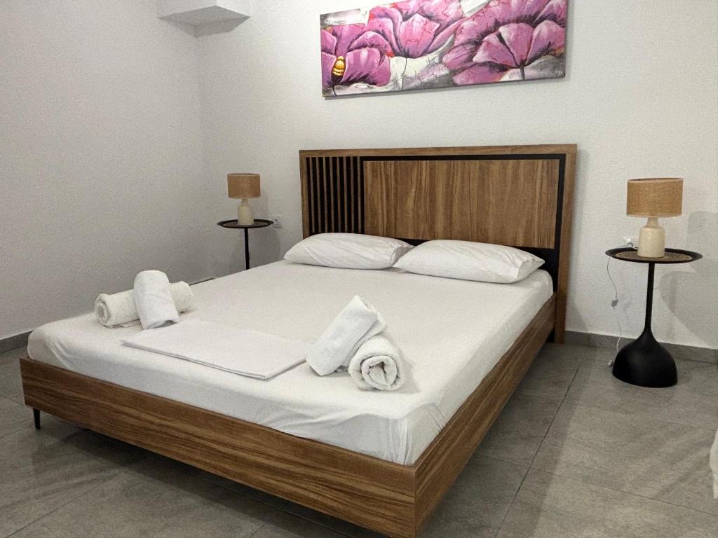 a bedroom with a bed with white sheets and towels at SunWaves Apartments in Keramoti