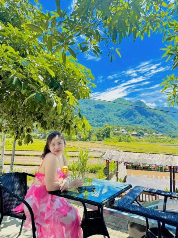 a little girl in a pink dress sitting at a table at Green Homestay Mai Chau in Mai Châu
