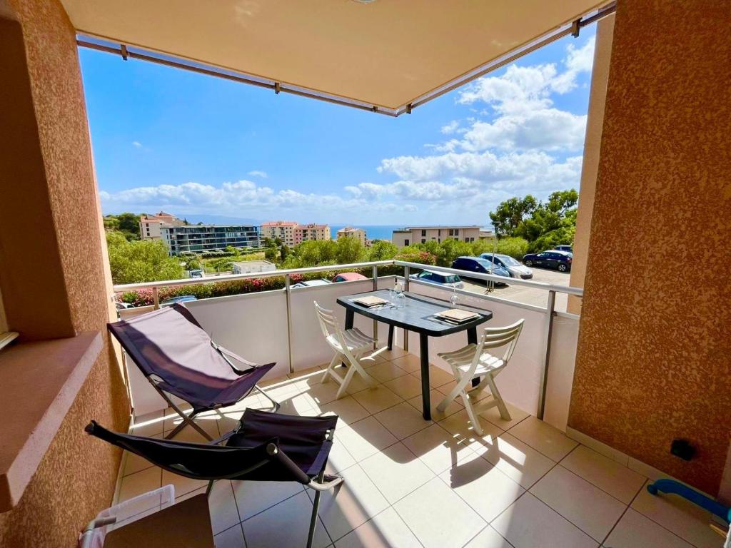 a balcony with a table and chairs on a balcony at Casamea - Vue Mer, Clim & Parking, Proche Plage in Ajaccio