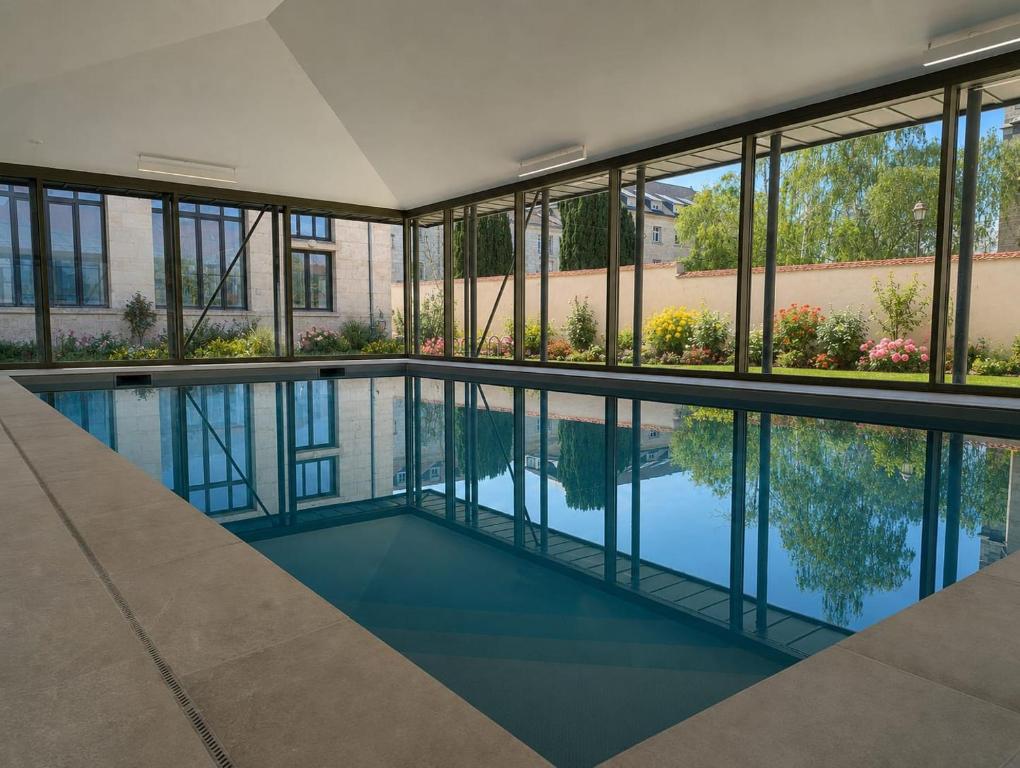 an empty swimming pool in a building with windows at ARBELLIA Appart'Hôtel Châlons en Champagne in Chalons en Champagne