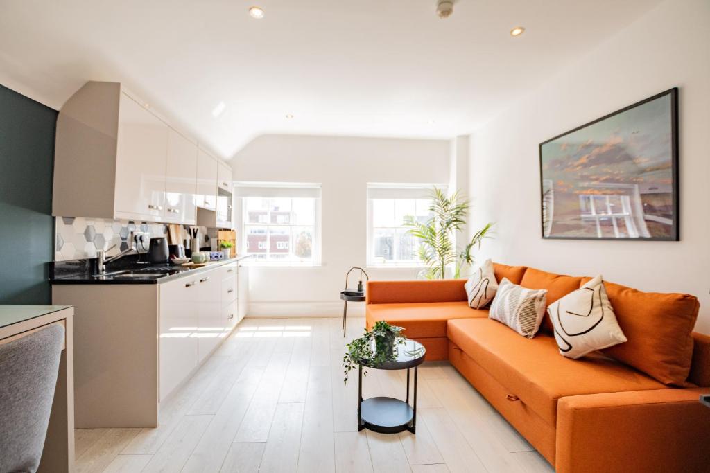 a living room with an orange couch and a kitchen at Dublin Central Suites in Dublin