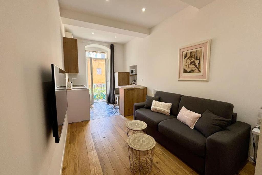 a living room with a black couch and a kitchen at Casamea - Studio, Terrasse, Clim, Centre hist in Ajaccio