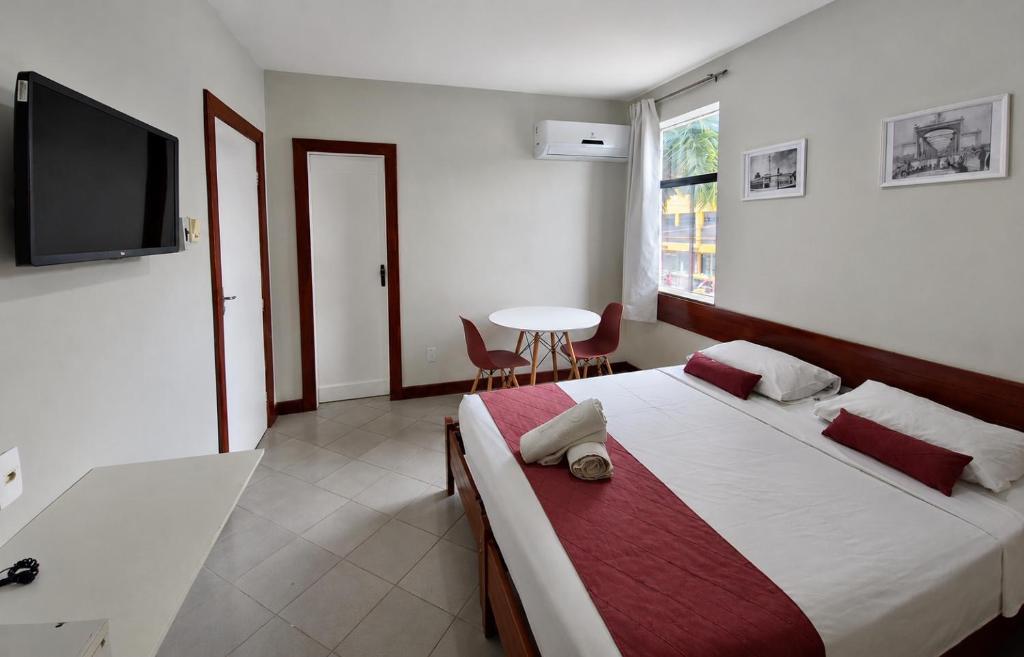 a bedroom with a bed and a tv and a table at Hotel Pousada Central in Feira de Santana