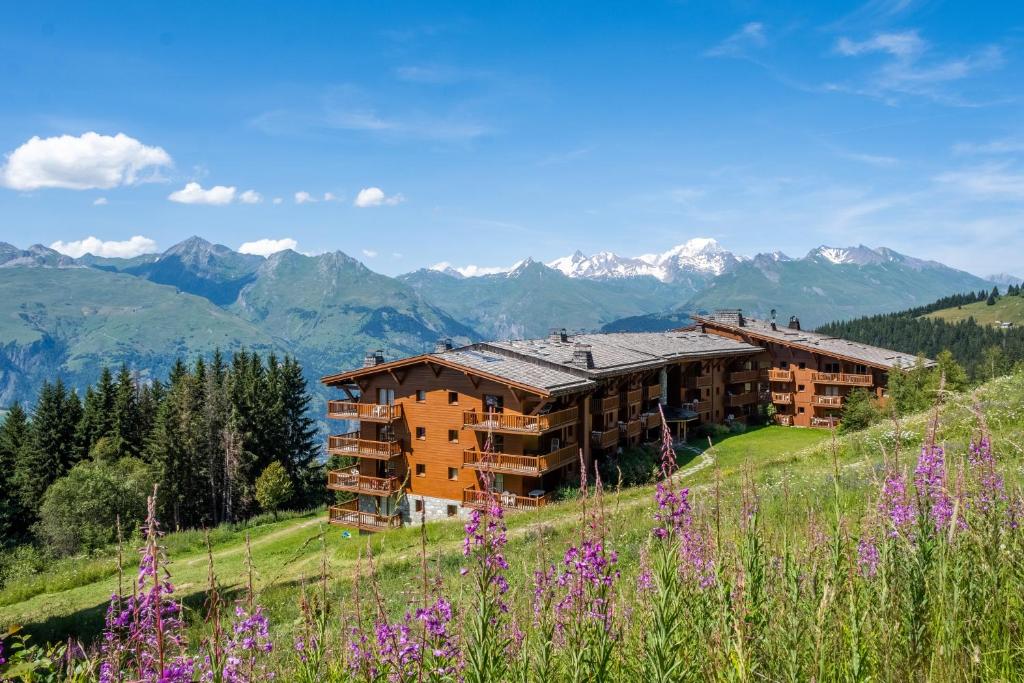 a building on a hill with mountains in the background at Résidence Pierre & Vacances Premium Le Roselend in Arc 1800