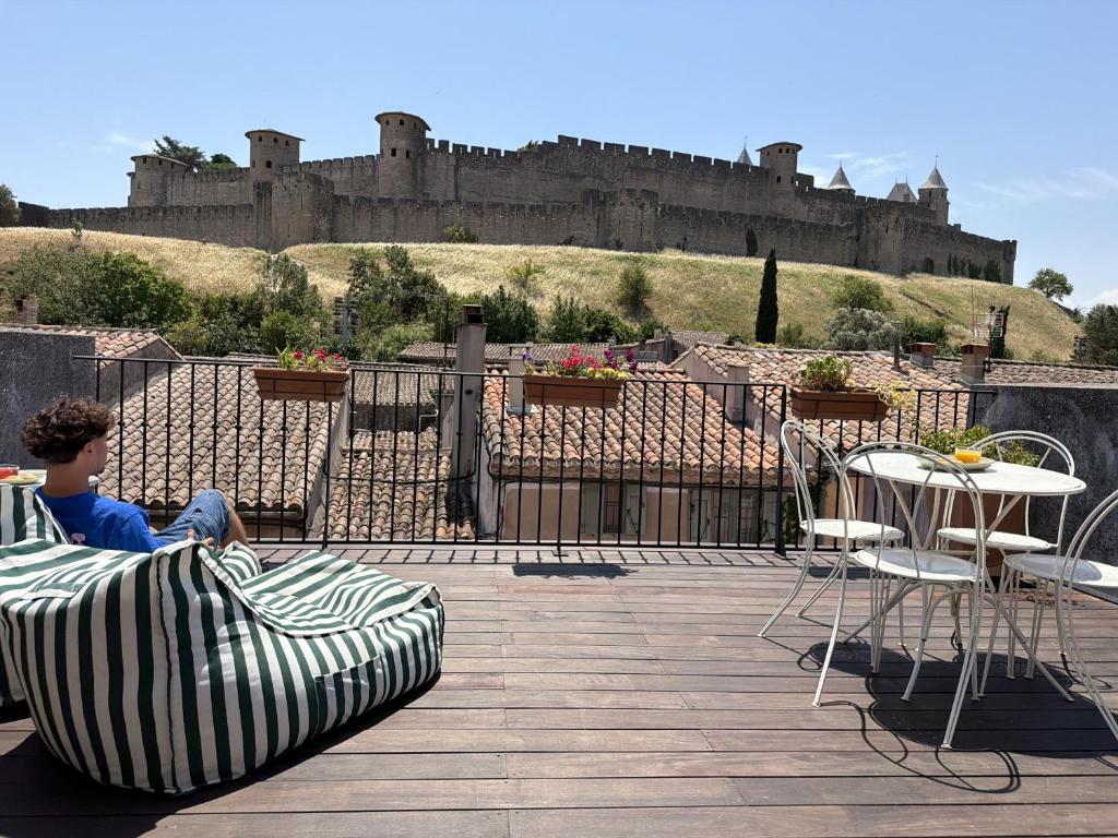 a boy sitting on a couch on a deck with a castle in the background at Les florentines in Carcassonne